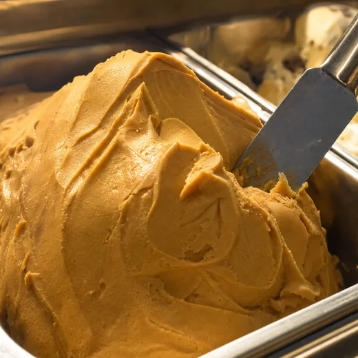 A tall stainless pan of dulce de leche helado moulded into a sculpted peak.